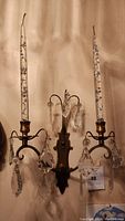 Full view of vintage French-style wall sconce with two candle holders and multiple hanging crystal prisms.