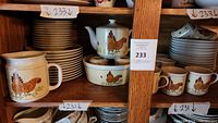 Wooden shelf display showing pitcher, teapot, small bowls, mugs and stacked plates