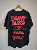 Back view of black T-shirt with large red text of 'Saint Pablo Tour', concert date Aug 30, 2016, and 'General Admission'.