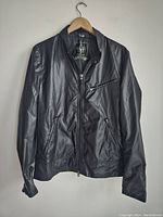 Front view of black Mackage light windbreaker jacket on hanger showing zippered pockets and collar.