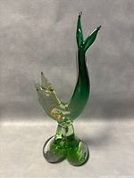 Front view of the green and clear Murano glass fish sculpture showing upward curved tail and gold flecks inside.