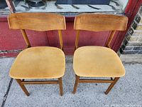 Front view showing two teak chairs with beige upholstered seats.