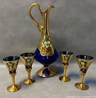 Full view of the decanter and four goblets showing overall condition, design and color scheme of the set.