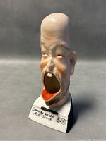 Side angle of ceramic lithograph ashtray figurine with text and musical notes on base.