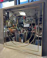 Front view of the 30x30 inch MCM wall mirror showing gold-tone frame with concentric square and oval geometrical design.