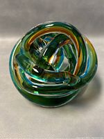 Front view of multicolored blown glass knot showing translucent swirling loops in ocean sunset colors