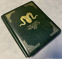 Closed hardcover album with embossed gold snake and geometric corner designs titled 'The Living Treasures of Asia'.