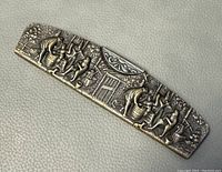 Close up photo of the front of the silver plated bas-relief pocket comb case, showing detailed figurative art scenes.