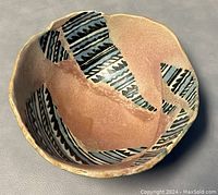Close-up of the oval-shaped pottery bowl showing black and blue traditional Navajo geometric patterns on a terracotta base.