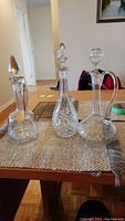 Three antique crystal decanters arranged on a table, showing overall shape and appearance.