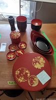 Full lot display showing variety of lacquerware including plates, bowls, trays, lidded container, and vase.