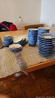 Photo of eleven stacked blue and white ceramic bowls with lids and matching plates spread out on a table.