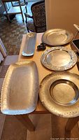 Five pewter serving dishes on table including three round and two long rectangular dishes