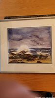Overall view of the framed oil painting showing the seascape with waves and rocks under clouds.
