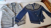 Two handmade Norwegian wool sweaters laid flat on bed. One is grey/white with multiple horizontal striped patterns, the other is blue with a Nordic patterned yoke.