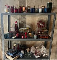 Shelving with various candles and candle holders in assorted colors and sizes, including glass holders and boxed candles.