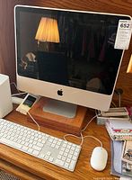 Front view of Apple iMac desktop with keyboard and mouse on a wooden desk.