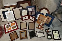 Photo showing arrangement of 20 new photo frames with various designs, sizes and colors including wood finishes, metal, and fabric wraps.