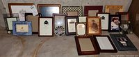 Wide view showing entire lot of 22 assorted small photo frames arranged on floor with visible tags and various finishes.
