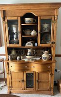 Front view of Pulsaki Keepsake honey oak hutch with glass doors showing displayed stoneware