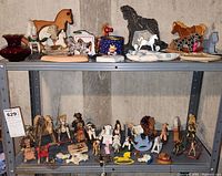 Two metal shelves holding various rocking horse figurines and related decorative objects in different materials and colors.