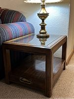 Side view of the vintage wooden side table showing the glass top and the open shelf below.