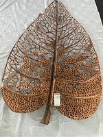 Photo showing the full birch leaf shaped metal wall decor with a perforated vein pattern and hammered texture, photographed on a white surface with a MaxSold tag.