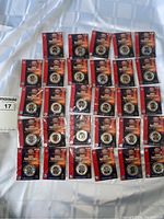 Overview of 31 sealed 2005 NFL Superstars Medallion collectible coins in blister packages laid out on a cloth.