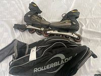 Side view of Nike rollerblades and black Rollerblade carrying bag on white surface.
