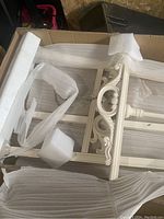 Photo shows disassembled white wooden easel parts with foam padding inside original box.