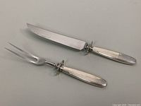 Complete set of 2-piece carving knife and fork showing full length and silver handles.