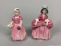Front view of two Royal Doulton porcelain figurines. Left: Bo Peep holding basket and flowers. Right: Tinkle Bell with hands on side folds of skirt.
