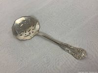 Full view of the sterling silver pierced bon bon spoon showing the pierced bowl and decorative handle.