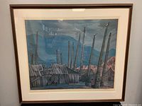 Full view of the framed print featuring totem poles and rustic wooden structures in an outdoor setting, under a cloudy blue sky.