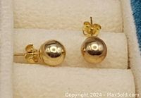 Close-up of pair of polished yellow gold ball stud earrings with butterfly backs inside the jewelry box.