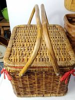 Top view of the large woven picnic basket with wooden handles folded over the lid tied with red fabric bows
