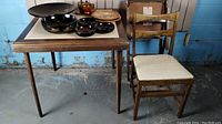 Photo of the folding table with bowls and plates displayed on top, and one folding chair set next to it on the floor