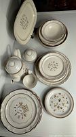 Photo showing a complete view of the partial Covington Idlewild stoneware set with teapot, sugar bowl, cream pitcher, small bowl, multiple plates including large oval platter.
