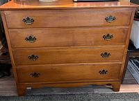 Front view showing the four drawer dresser with metal handles and wood finish.