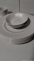 Stack of Johnson Brothers Athena dinner plates and small dessert bowls showing embossed fluted pattern around rims.