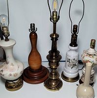 Five lamps and one vase arranged close together showing various designs and materials.