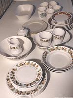 Set of partial Noritake Progressions Day Dream pattern dishes on white table including plates, bowls, cups, creamer, and covered sugar bowl.