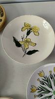 Round plate featuring yellow flower motif and hand-painted design seen on top surface