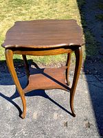 Full view of the quarter sawn oak side table showing curved legs and lower shelf, outdoor setting.