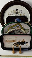 Stacked vintage tin trays showing various decorative and advertising designs