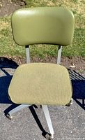 Front view of vintage office chair showing sage green fabric seat and vinyl backrest attached to metal frame with caster wheels on the base.
