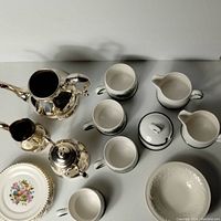 Top view of entire tea set, showing silver plate pieces on left, Wedgwood cups, creamers, sugar bowl on right, and Ambrosia plates at bottom.