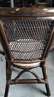 Back view of one of the dark brown bamboo chairs showing lattice wicker back and bamboo frame structure