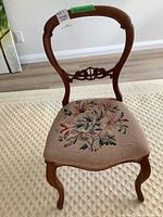 Full view of the antique side chair showing the balloon style carved rosewood back and needlepoint seat with floral needlework.