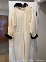 Full front view of the cream wool coat with black faux fur trim on hood and cuffs, front zipper closure and pockets visible.